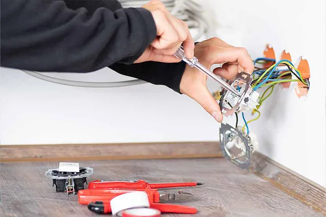 Elektriker installiert Steckdosen oder Verkabelung im Rohbau.